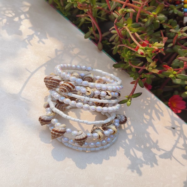 bracelet with white beads paired with a small shankha (conch shell)